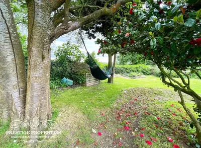a hammock hanging from a tree in a garden at Millstream Barn by Prestige Properties SA in Millom