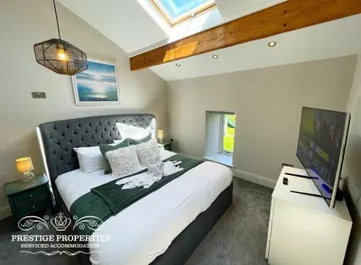 a bedroom with a large bed and a television at Millstream Barn by Prestige Properties SA in Millom