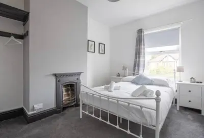 a white bedroom with a bed and a fireplace at Spacious Town House in Lytham St Annes