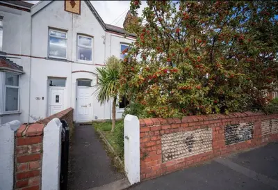 a brick wall with a tree in front of a house at Spacious Town House in Lytham St Annes
