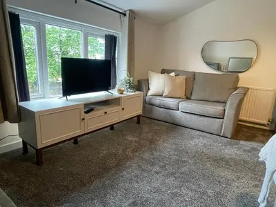 a living room with a couch and a flat screen tv at Slick Space for a Standish Stay in Standish