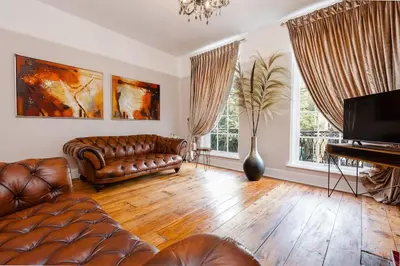 a living room with a leather couch and a piano at City Centre Georgian Listed Townhouse in Liverpool