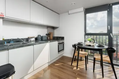 a kitchen with white cabinets and a table and a window at Chavasse Apartments, 1 Bed Studio, Parking - Pass the Keys in Liverpool