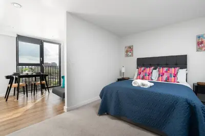 a bedroom with a bed with a blue blanket and a table at Chavasse Apartments, 1 Bed Studio, Parking - Pass the Keys in Liverpool