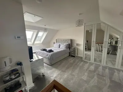 a large bedroom with a bed and a mirror at Drey Close in Formby