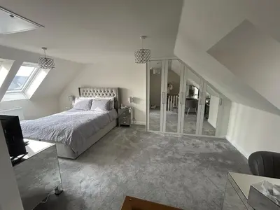 a white bedroom with a bed and a staircase at Drey Close in Formby