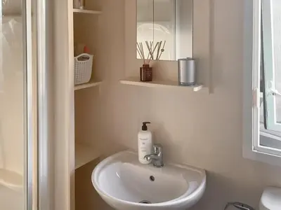 a white bathroom with a sink and a mirror at Sea Breeze in Heysham