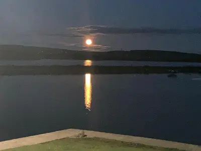 a full moon rising over the water at night at Lakes edge view in Millom