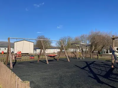 a playground with a swing set in a park at Lakes edge view in Millom