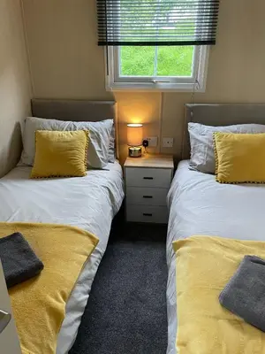 a bedroom with two beds with yellow pillows and a window at Lakes edge view in Millom