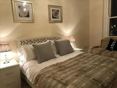 a bedroom with a large bed with two lamps and a chair at The Paradise Suite in Southport
