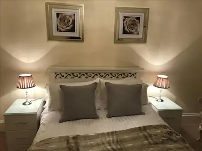 a bedroom with a bed with two nightstands and two lamps at The Paradise Suite in Southport