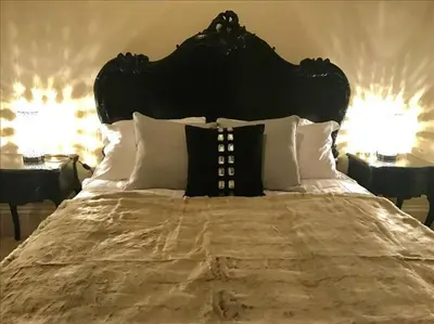 a large bed with a black headboard and white pillows at The Paradise Suite in Southport