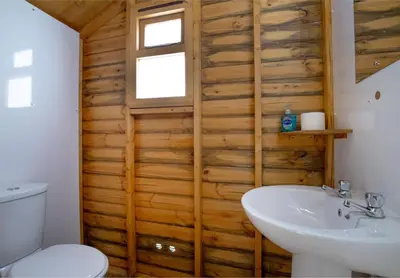 a bathroom with a wooden wall with a toilet and a sink at Bleasdale at Lantern and Larks in Chipping