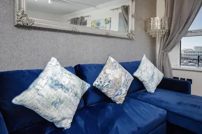 a blue couch with pillows on it with a mirror at The Place by Sasco - Free Parking in Blackpool