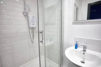 a white bathroom with a shower and a sink at HARRISON SUITE 6 BEDS in Liverpool