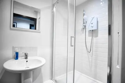 a white bathroom with a sink and a shower at HARRISON SUITE 6 BEDS in Liverpool