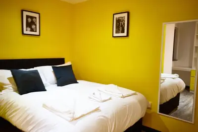 a bedroom with two beds with yellow walls and a mirror at HARRISON SUITE 6 BEDS in Liverpool