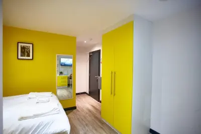 a bedroom with a yellow wall and a bed at HARRISON SUITE 6 BEDS in Liverpool