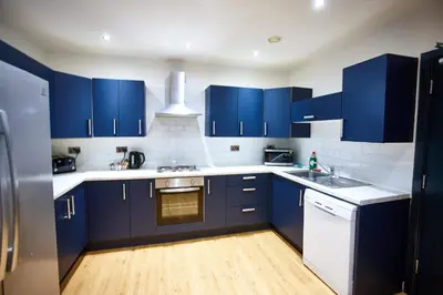 a kitchen with blue cabinets and white appliances at HARRISON SUITE 6 BEDS in Liverpool