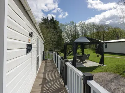 a deck with a gazebo next to a house at Ladybird Lodge in Carnforth