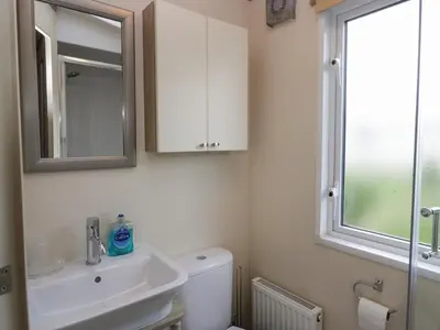 a bathroom with a toilet and a sink and a mirror at Ladybird Lodge in Carnforth