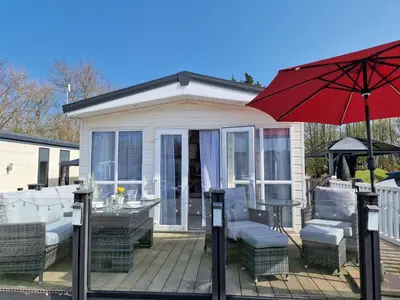 a deck with a table and chairs and an umbrella at Ladybird Lodge in Carnforth