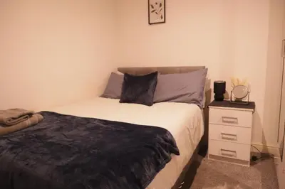 a bedroom with a bed and a night stand at City Centre - Modern Apartment in Liverpool