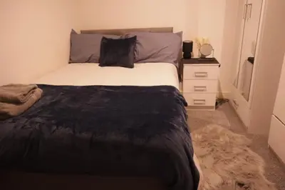 a bedroom with a bed with a black blanket and a dresser at City Centre - Modern Apartment in Liverpool
