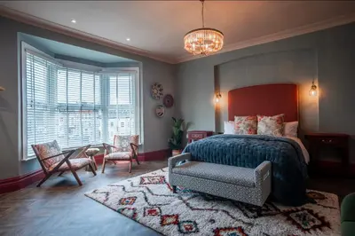 a bedroom with a bed and a chair and a table at Luxury Seaside 5 Bed - 10 Mins Walk to Beaches in New Brighton