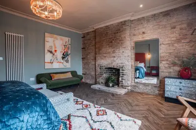 a living room with a fireplace and a green couch at Luxury Seaside 5 Bed - 10 Mins Walk to Beaches in New Brighton