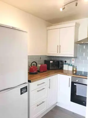 a kitchen with white cabinets and a refrigerator at Central Stylish 2Bedroom flat with free parking in Liverpool