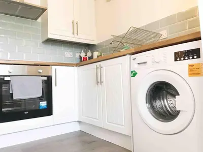 a kitchen with a washing machine and a microwave at Central Stylish 2Bedroom flat with free parking in Liverpool