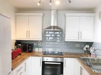 a kitchen with white cabinets and a stove top oven at Central Stylish 2Bedroom flat with free parking in Liverpool