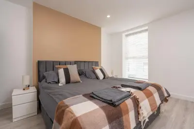 a bedroom with a bed with a blanket and a window at Cosy central apartment - free nearby parking in Liverpool