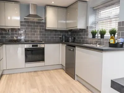 a kitchen with white cabinets and stainless steel appliances at The bungalow at 46 Church St in Chorley