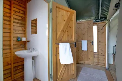 a bathroom with a wooden door and a sink at Plover - Bleasdale in Chipping