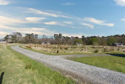 a gravel road leading into a field with houses at Redshank - Bleasdale in Chipping