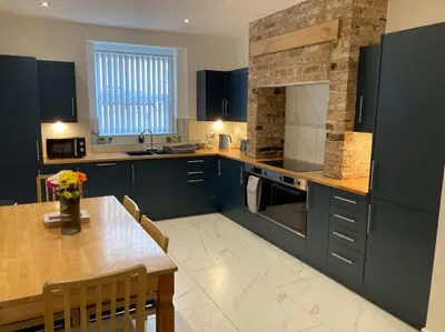 a kitchen with blue cabinets and a table and a brick wall at Exceptional 5 bed house near City Centre in Liverpool