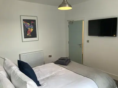 a bedroom with a white bed with a flat screen tv at Exceptional 5 bed house near City Centre in Liverpool