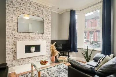 a living room with a brick wall and a mirror at Willow House - 2-Bedroom House In Merseyside! in Birkenhead