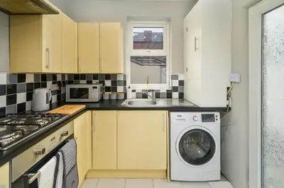 a kitchen with a washing machine and a sink at Willow House - 2-Bedroom House In Merseyside! in Birkenhead