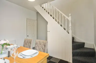 a dining room with a table and a staircase at Willow House - 2-Bedroom House In Merseyside! in Birkenhead