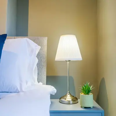 a lamp on a blue nightstand next to a bed at Willow House - 2-Bedroom House In Merseyside! in Birkenhead