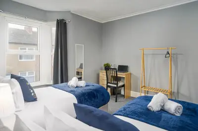 a bedroom with two beds and a desk with a computer at Willow House - 2-Bedroom House In Merseyside! in Birkenhead