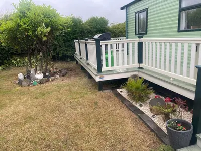 a yard with a green house with a white deck at 147a Port Haverigg in Millom