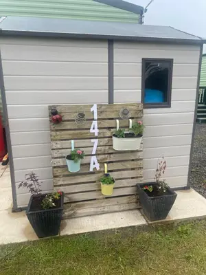 a shed with potted plants on the side of it at 147a Port Haverigg in Millom