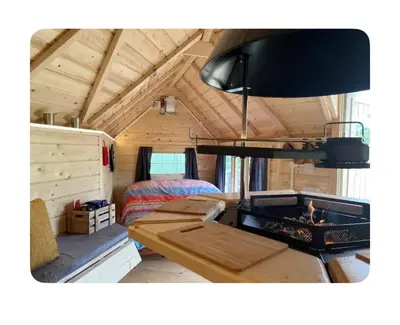 a living area of a tiny house with a fireplace at Off GRID Hobbit Hut with Wood Burning Hot tub NO SHOWER in Hapton