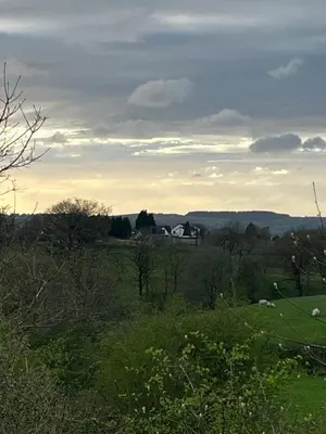 a view of a field with a house in the distance at Off GRID Hobbit Hut with Wood Burning Hot tub NO SHOWER in Hapton