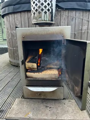 a grill with a fire in it on a deck at Off GRID Hobbit Hut with Wood Burning Hot tub NO SHOWER in Hapton